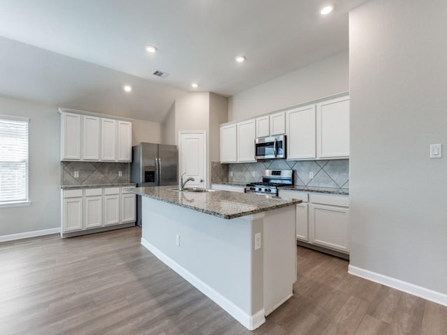 kitchen featuring visible vents, appliances with stainless steel finishes, a kitchen island with sink, white cabinets, and a sink