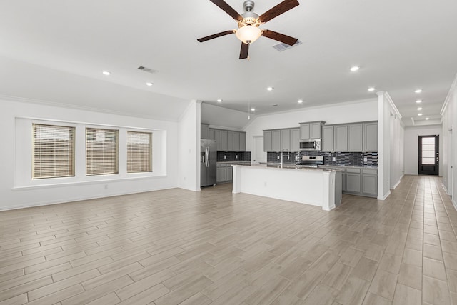 kitchen with visible vents, open floor plan, appliances with stainless steel finishes, gray cabinets, and a center island with sink