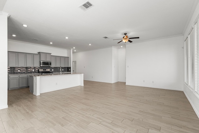 kitchen featuring stainless steel appliances, visible vents, gray cabinetry, open floor plan, and an island with sink