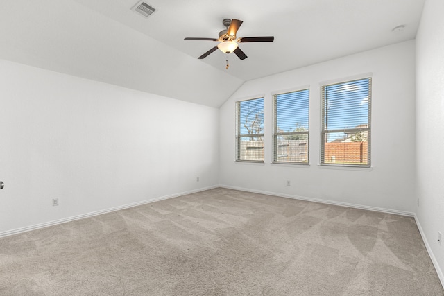 spare room featuring light carpet, baseboards, visible vents, a ceiling fan, and vaulted ceiling