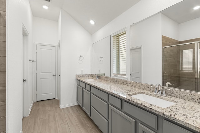 bathroom with a stall shower, a sink, baseboards, and double vanity