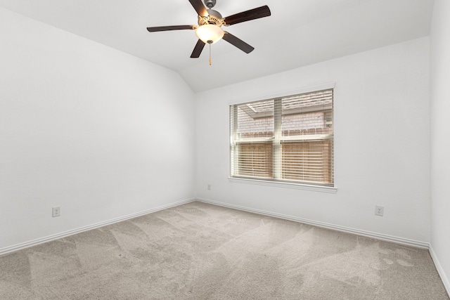 carpeted spare room with vaulted ceiling, a ceiling fan, and baseboards