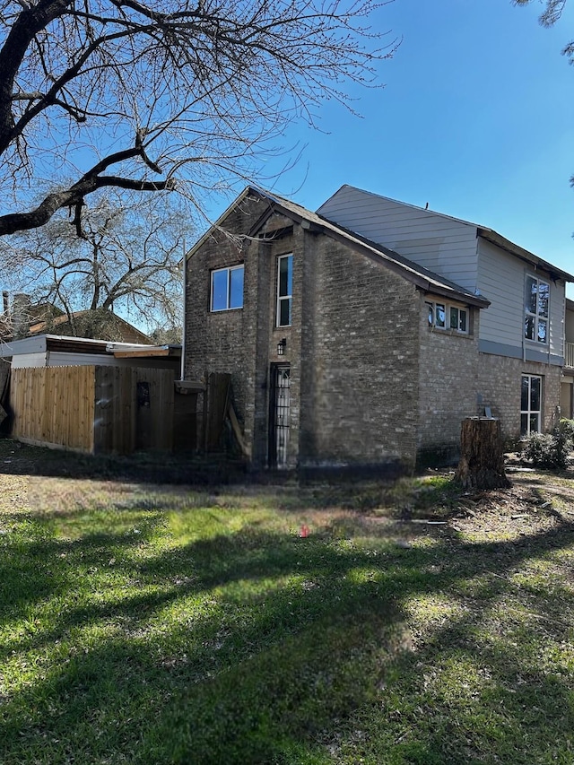 back of house with a yard, brick siding, and fence