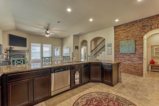 kitchen featuring arched walkways, stainless steel dishwasher, a sink, and light stone counters