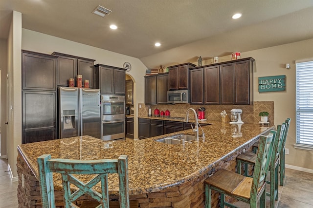 kitchen featuring visible vents, arched walkways, a breakfast bar area, a peninsula, and stainless steel appliances