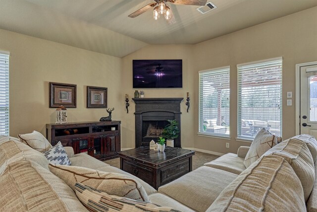 living area with visible vents, baseboards, lofted ceiling, ceiling fan, and a fireplace