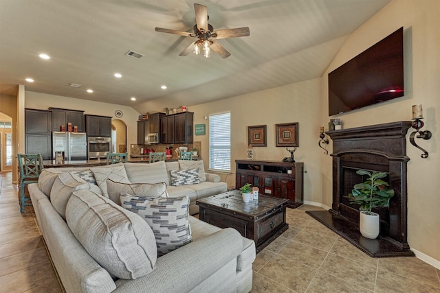 living room featuring arched walkways, visible vents, a ceiling fan, vaulted ceiling, and baseboards