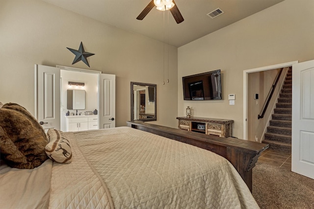 bedroom with lofted ceiling, connected bathroom, visible vents, a ceiling fan, and dark colored carpet