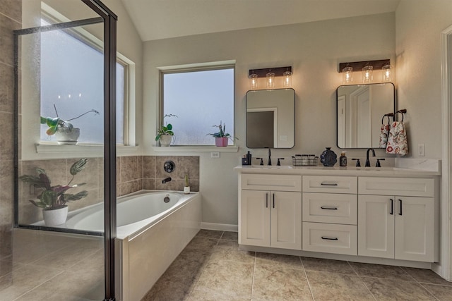 bathroom featuring lofted ceiling, double vanity, a sink, and a bath