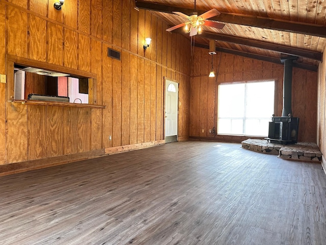 unfurnished living room with visible vents, lofted ceiling with beams, a wood stove, wood finished floors, and wooden ceiling