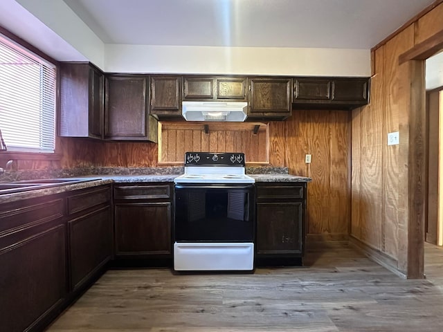 kitchen featuring under cabinet range hood, white range with electric stovetop, light wood-style floors, and wood walls