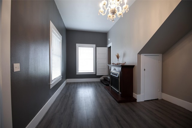 additional living space with a notable chandelier, baseboards, and dark wood-type flooring