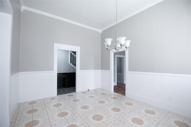 spare room with a wainscoted wall, ornamental molding, and a notable chandelier