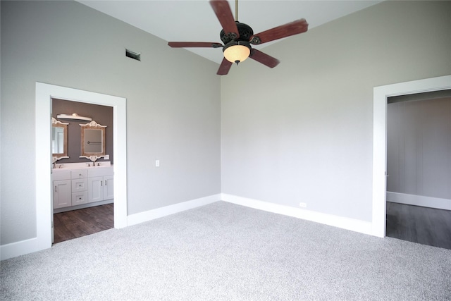 unfurnished bedroom with visible vents, baseboards, ensuite bath, vaulted ceiling, and dark colored carpet