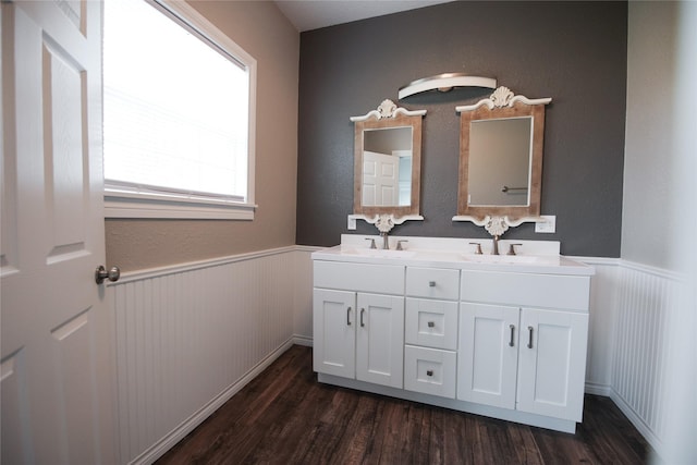 full bathroom featuring double vanity, wainscoting, and wood finished floors