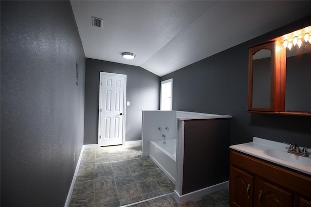 bathroom featuring a garden tub, visible vents, vanity, vaulted ceiling, and baseboards