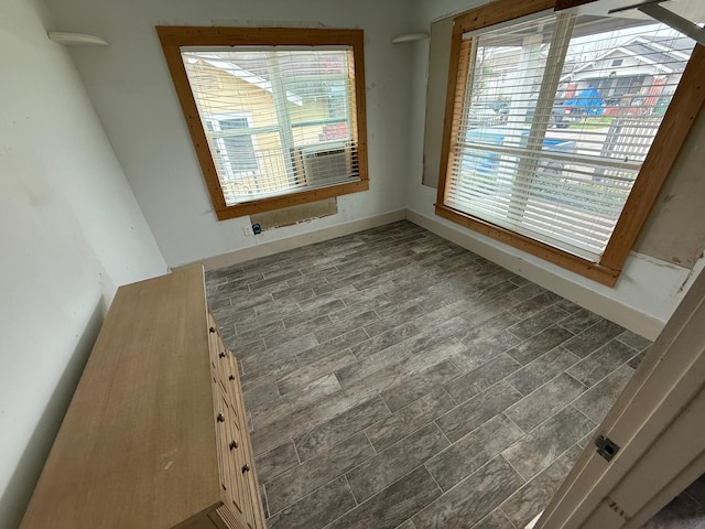 spare room featuring dark wood-type flooring, cooling unit, and baseboards