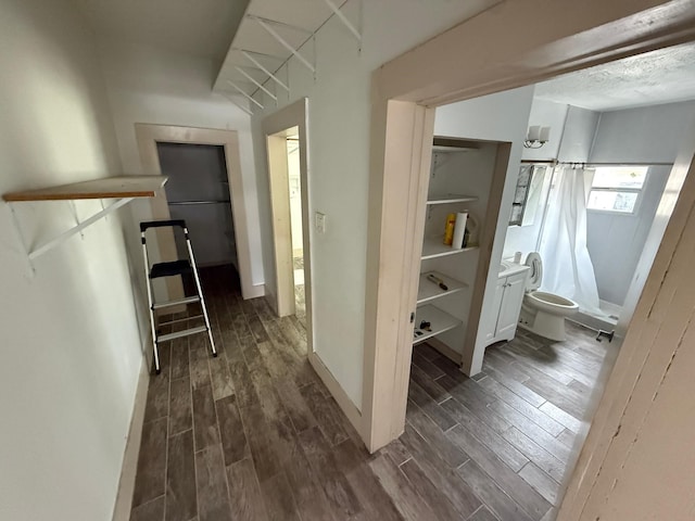 corridor featuring wood tiled floor, baseboards, and a textured ceiling