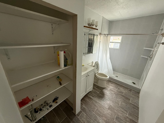 bathroom with a stall shower, toilet, a textured ceiling, vanity, and wood finish floors