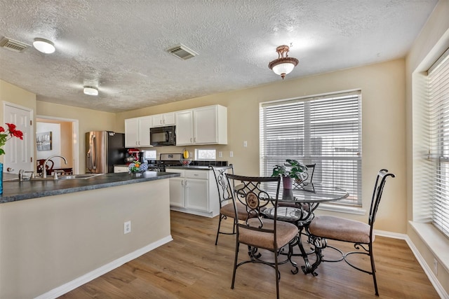 kitchen with stainless steel appliances, dark countertops, visible vents, and white cabinets