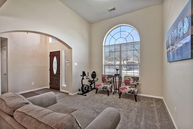 interior space with arched walkways, visible vents, a towering ceiling, and baseboards