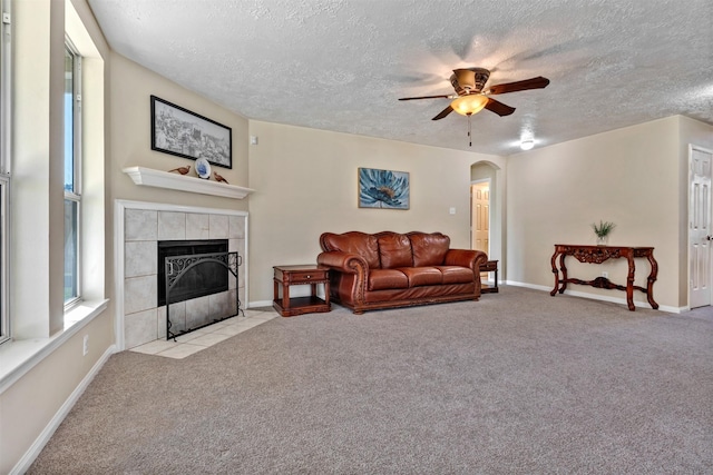 living room featuring light carpet, a fireplace, arched walkways, and baseboards