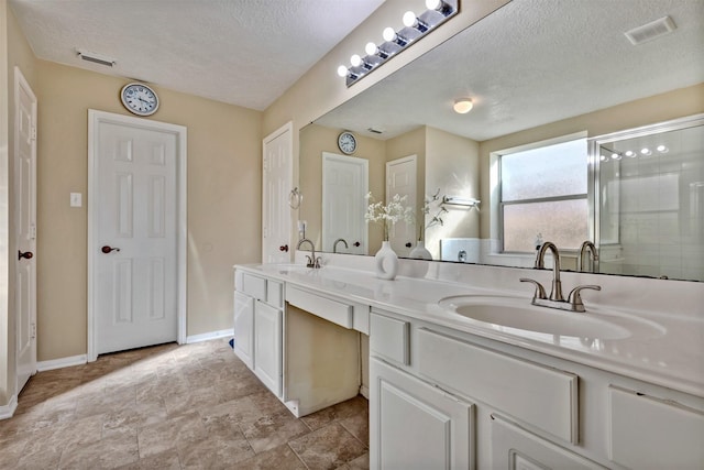 full bathroom featuring a textured ceiling, double vanity, a sink, and visible vents