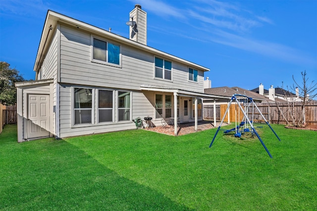 back of house with a fenced backyard, a chimney, a lawn, and a playground