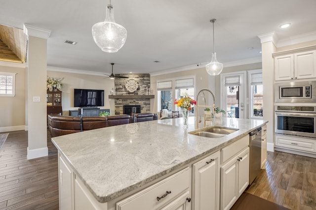 kitchen featuring decorative light fixtures, stainless steel appliances, visible vents, a kitchen island with sink, and a sink