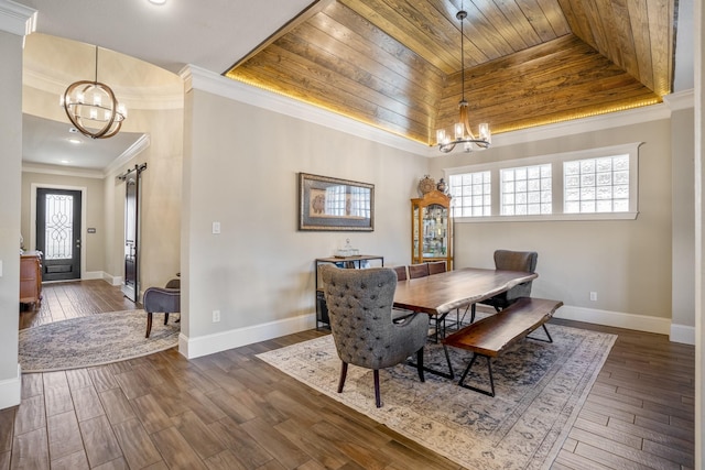 dining room featuring a barn door, dark wood finished floors, a tray ceiling, crown molding, and a chandelier