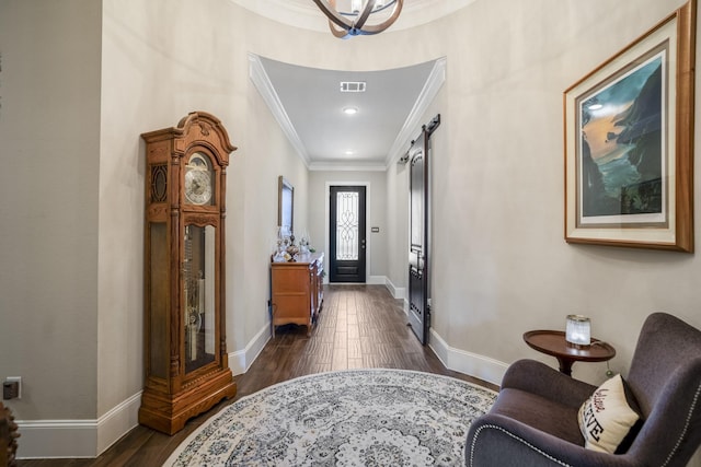 foyer entrance featuring visible vents, a barn door, dark wood-type flooring, ornamental molding, and baseboards