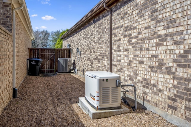 exterior details featuring a power unit, brick siding, cooling unit, and fence