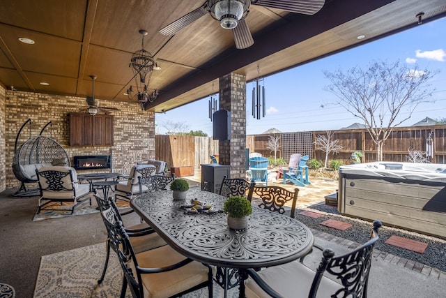 view of patio featuring a hot tub, a fenced backyard, a ceiling fan, and outdoor dining space