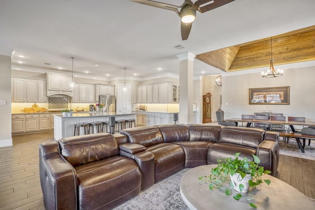 living area featuring ornamental molding, visible vents, light wood-style flooring, and ornate columns