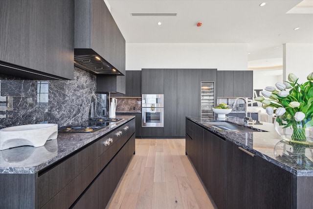 kitchen with light wood finished floors, modern cabinets, a sink, and stovetop