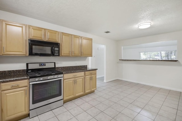 kitchen featuring a textured ceiling, stainless steel gas range, dark stone counters, black microwave, and baseboards