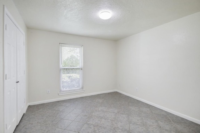 unfurnished room featuring baseboards and a textured ceiling