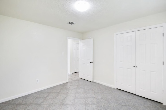 unfurnished bedroom featuring a closet, visible vents, a textured ceiling, and baseboards