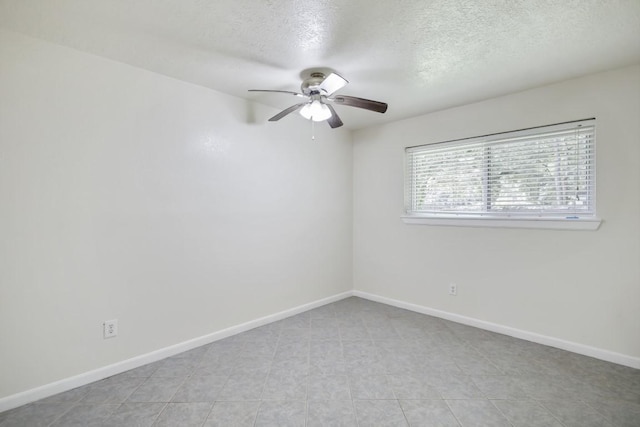 empty room featuring ceiling fan, baseboards, and a textured ceiling