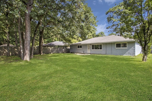 rear view of property with a yard, brick siding, and a fenced backyard