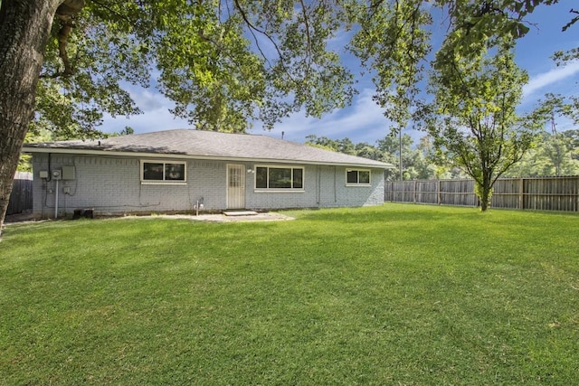 back of house featuring a fenced backyard, a yard, and brick siding