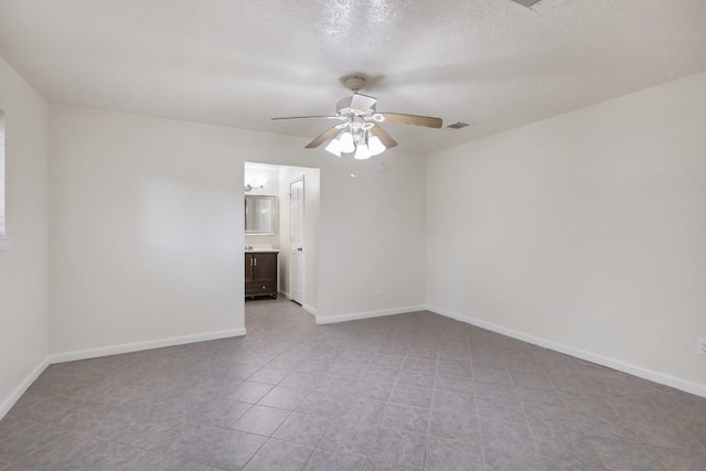 empty room with visible vents, ceiling fan, a textured ceiling, and baseboards