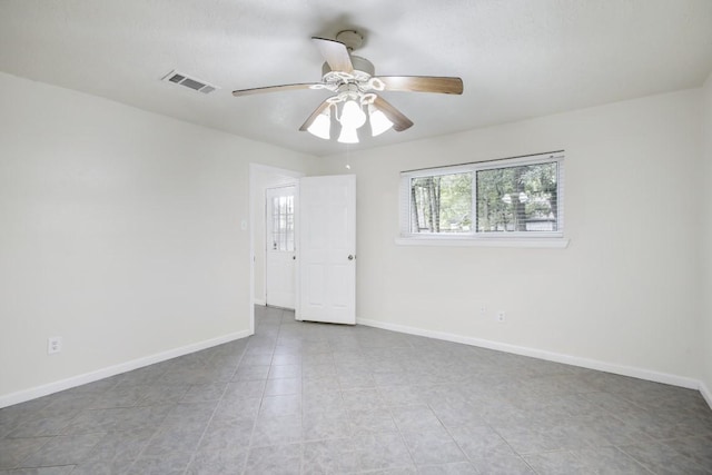 spare room with baseboards, visible vents, and a ceiling fan