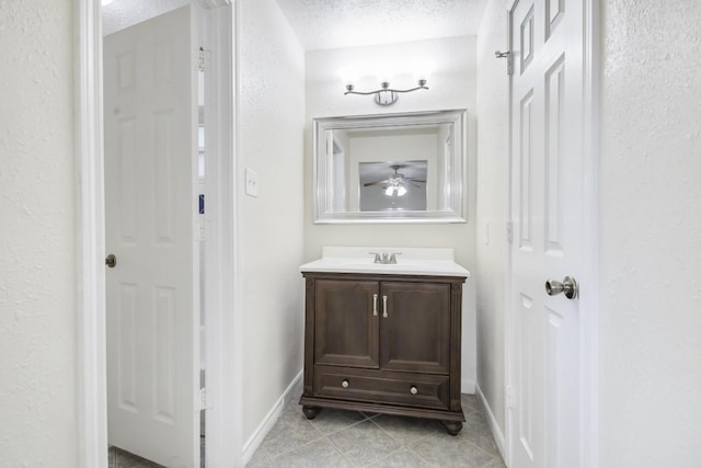 bathroom featuring baseboards, a textured wall, tile patterned flooring, a textured ceiling, and vanity