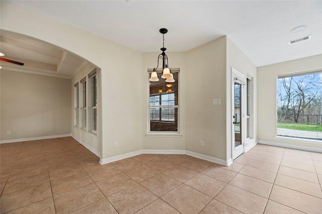 unfurnished dining area with light tile patterned floors, arched walkways, ceiling fan with notable chandelier, visible vents, and baseboards