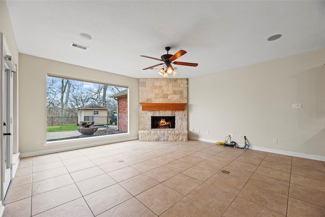 unfurnished living room with light tile patterned floors, baseboards, visible vents, and a stone fireplace