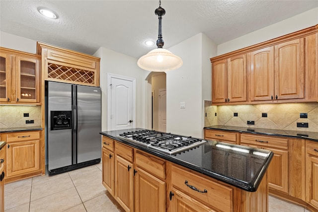 kitchen with light tile patterned floors, arched walkways, a kitchen island, glass insert cabinets, and appliances with stainless steel finishes