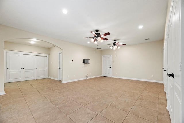 empty room featuring arched walkways, light tile patterned floors, recessed lighting, ceiling fan, and baseboards