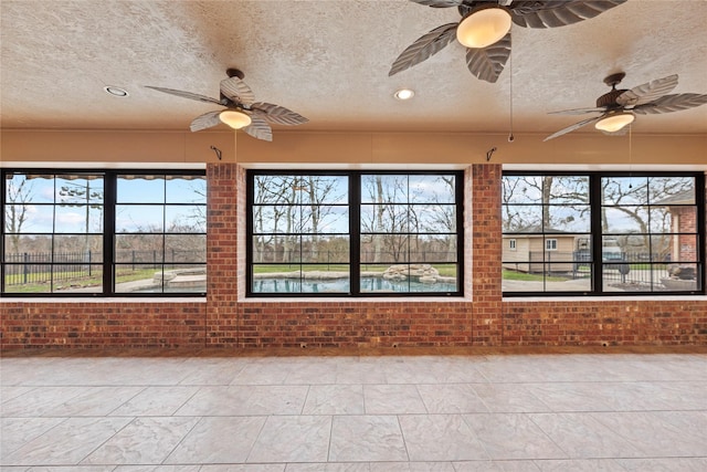 unfurnished sunroom with ceiling fan and a wealth of natural light