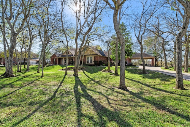 view of front of home with driveway, brick siding, and a front yard